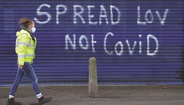A pedestrian walks past graffiti reading u2018Spread (love), not Covidu2019 on the shutters of a closed shop in Hull, in northeast England, yesterday. Hull will return to the Englandu2019s highest coronavirus category, Tier 3, when England exits its second lockdown and re-enters a tiered system of toughened regional restrictions tomorrow.