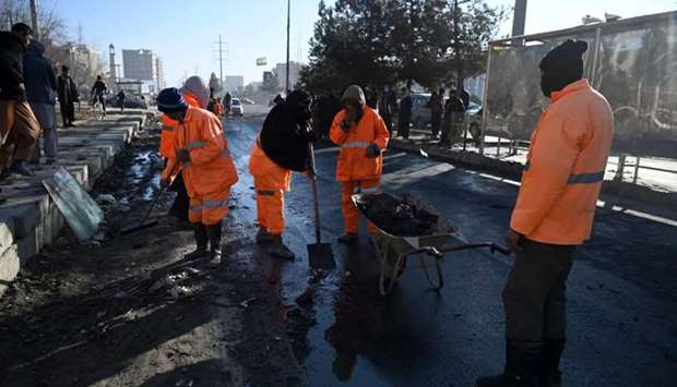 Municipal workers clean and remove debris along a street after multiple rockets were fired in the Afghan capital Kabul