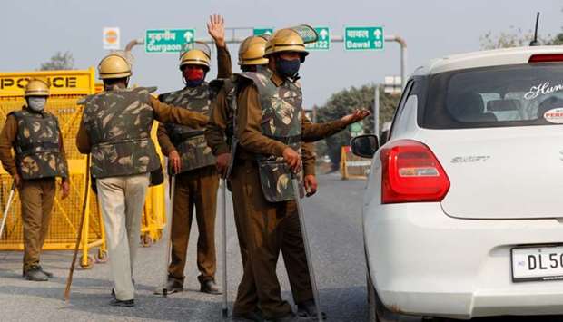Police officers in riot gear check a car for protesting farmers at a state border on a national highway in Rewari district in the northern state of Haryana, near New Delhi, India