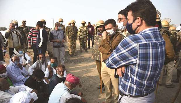 Farmers sit on the ground as police personnel block a highway on the Haryana-Rajasthan border to stop the farmers from joining protests in Delhi against the recent agricultural reforms, in Rewari district, yesterday.