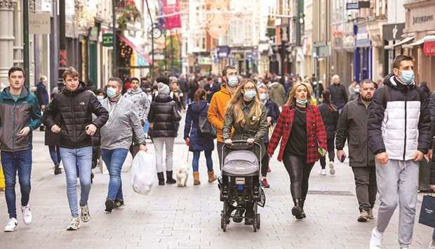 Pedestrians, some wearing face masks or coverings due to the Covid-19 pandemic, walk along a busy shopping street in Dublin yesterday.
