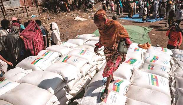 A woman walks over piles of sacks of wheat during a distribution of food organised by the Ethiopian government in the city of Alamata.