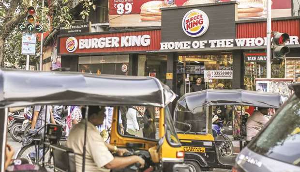 Auto-rickshaws moving outside a Burger King restaurant in Mumbai. Burger King India Ltd more than doubled in its Mumbai trading debut yesterday from its initial public offering price.
