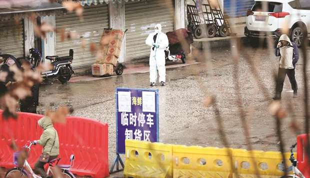 File photo taken on January 10, 2020 shows a worker in a protective suit at the closed seafood market in Wuhan, Hubei province, China.