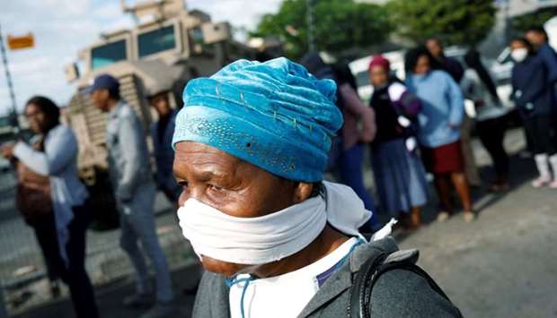 An elderly woman covers her face with a makeshift mask as people queue to collect social grants and shop during a 21 day nationwide lockdown aimed at limiting the spread of coronavirus disease  in Khayelitsha township near Cape Town, South Africa, March 31.