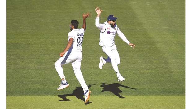 Indian captain Virat Kohli reacts with bowler Ravichandran Ashwin (L) on day 2 of the first Test match against Australia at the Adelaide Oval.