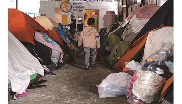 A boy walks amid tents at the Juventud 2000 migrant shelter in Tijuana, Mexico. The coronavirus pandemic has left migrants seeking asylum in the United States stranded along the US-Mexico border for almost a year. The United Nations commemorated yesterday, December 18, International Migrants Day.