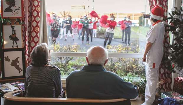 Residents watch through the window as medical workers perform during a Christmas party at Le Gatinais Korian retirement home in Maisse, near Paris.
