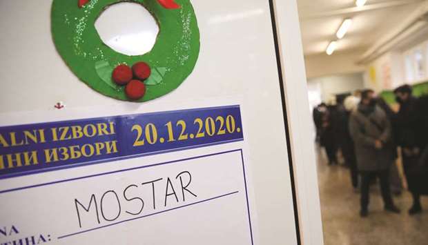 An information board is seen as people queue to cast their ballots during the local election at a polling centre in a school in Mostar, Bosnia and Herzegovina.