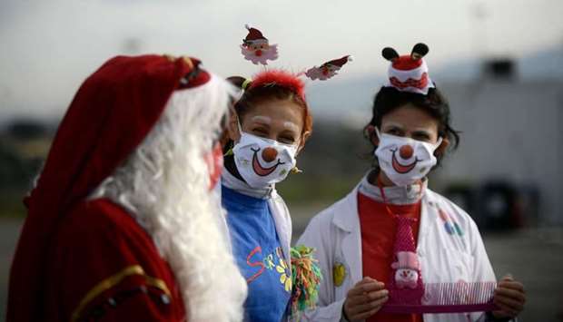 Medical workers dressed as clowns and Santa Claus entertain people lined up in their car to undergo a Covid-19 swab test for coronavirus, yesterday, at a drive-through testing site of the Tor Vergata hospital in Rome
