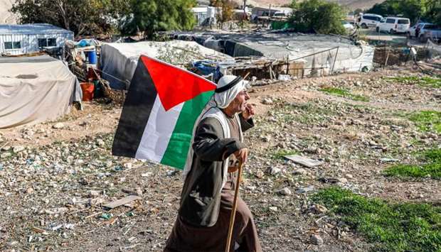 A Bedouin man walks with a Palestinian flag in the village of Khan al-Ahmar