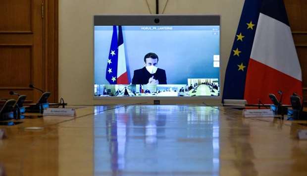 :France's President Emmanuel Macron, who tested positive for the coronavirus disease, is seen on a screen as he attends by video conference a round table for the weekly cabinet meeting of the government at the Army Ministry in Paris yesterday