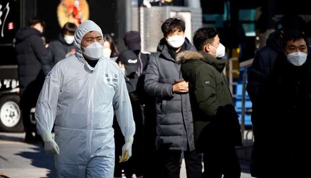 A South Korean soldier wearing a protective suit walks past people who wait in a line to undergo a coronavirus disease test at a coronavirus testing site which is temporarily set up near a subway station in Seoul, South Korea, December 17