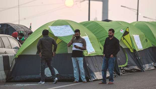 Farmers stand in front of their tents on a blocked highway during a protest against the central governmentu2019s recent agricultural reforms in Ghazipur, along the Delhi-Uttar Pradesh state border, yesterday.