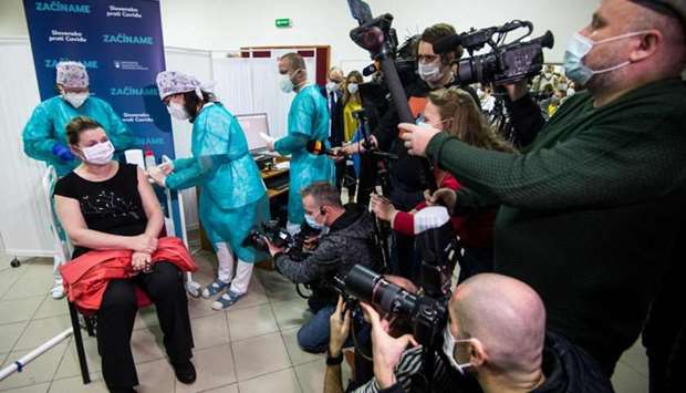A woman sits on a chair in front of medias as she receives a vaccination against the novel coronavirus Covid-19 on December 26 in the faculty hospital in Nitra, western Slovakia