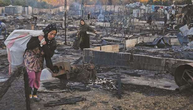 Syrian refugees salvage belongings from the wreckage of their shelters at a camp set on fire overnight in the northern Lebanese town of Bhanine yesterday.