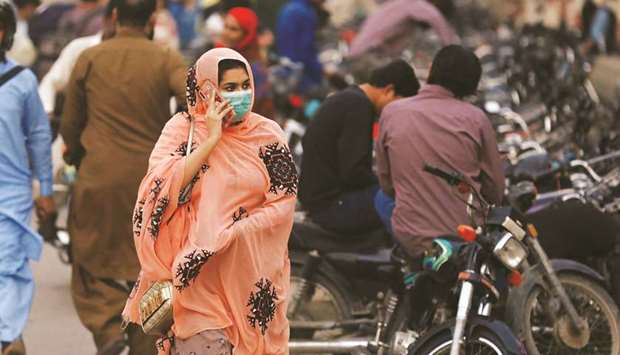 PROTECTION: A woman wears a protective mask while walking along a road as the outbreak of the coronavirus disease continues in Karachi yesterday. (Reuters)
