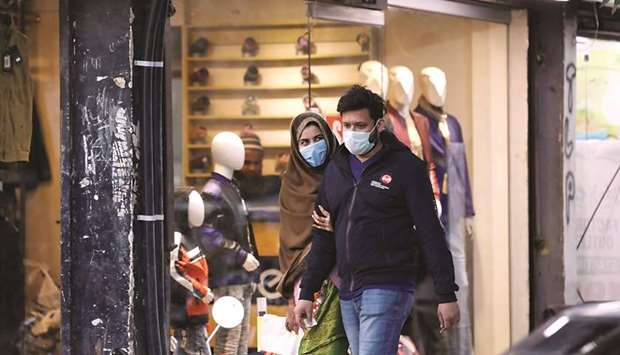 A couple wearing protective masks walks along a market as the outbreak of coronavirus disease continues in the southern port city of Karachi. (Reuters)
