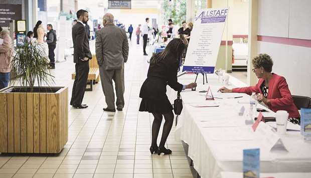 A job seeker (centre) takes a business card at a job fair in Belmont, New Hampshire (file). Initial claims for state unemployment benefits slid to a seasonally adjusted 787,000 for the week ended December 26, from 806,000 in the prior week, the Labour Department said yesterday.