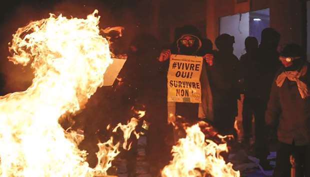 A demonstrator holds a sign reading u2018Living, yes! Surviving, no!u2019 during a protest in Paris.