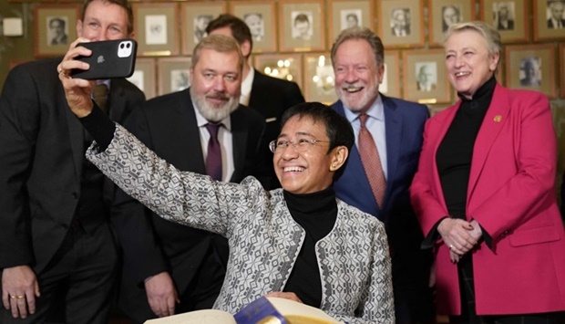 Nobel Peace Prize winner Maria Ressa takes a selfie with the Nobel Committee and co-prize winner Dimitrij Muratov after a press conference at the Norwegian Nobel Institute in Oslo on December 9, the day before the awarding ceremony of the Nobel Peace Prize.