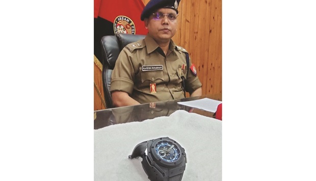 Police officer Rakesh Roushan sits next to a stolen watch, which was customised for Diego Maradona, in Sivasagar yesterday. (AFP)