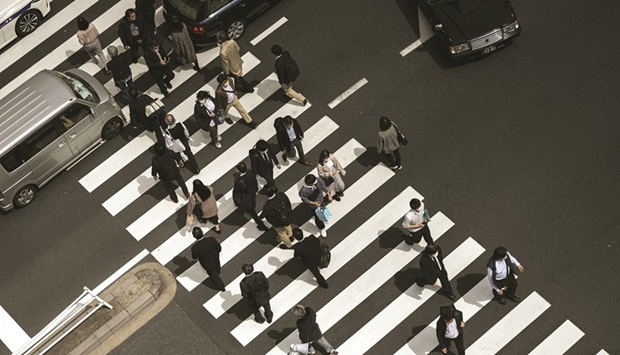 Pedestrians including office employees cross a street in Tokyou2019s Shimbashi area at lunchtime. Pushing up worker pay that has languished for years wonu2019t be easy, though, especially given that Japanu2019s economy has lagged other developed nations in recovering from the pandemic.
