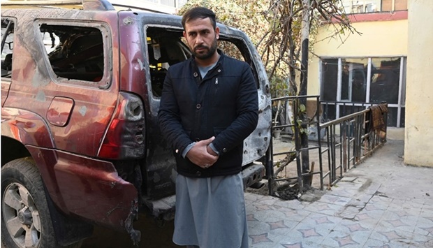 Aimal Ahmadi, whose daughter Mailka and his elder brother Zimarai Ahmadi was among 10 relatives killed by a wrongly directed US drone strike on August 29, stands near a car, which was damaged during the strike, outside his house in Kabul on December 14. AFP