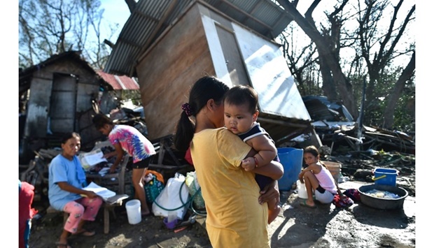 Residents gather next to their destroyed house in Carcar, Philippines' Cebu province yesterday, days after Super Typhoon Rai hit the city.