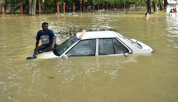 A man sits on the bonnet of a car as he waits to be evacuated by a rescue team in Shah Alam, Selangor yesterday, as Malaysia faces some of its worst floods for years.