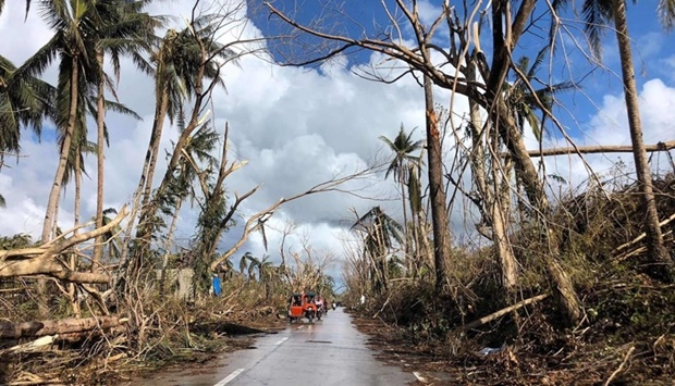 Tricycles speeds past fallen coconut trees at the height of Super Typhoon Rai along a highway in Del Carmen town, Siargao island on December 20, days after Super Typhoon Rai hit the province.