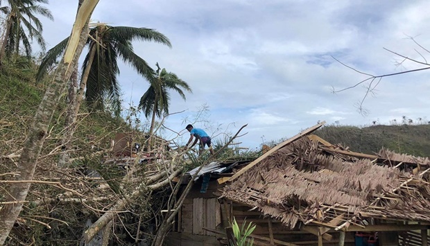 A resident stands atop his damaged house at a village in Dapa town on Siargao island, days after Super Typhoon Rai barelled through the island. 