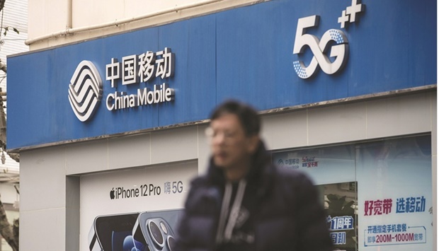 A pedestrian walks past a China Mobile store in Shanghai. The state-run company, which was removed from the New York Stock Exchange earlier this year due to an investment ban ordered by former US president Donald Trump, will exercise its over-allotment option for the offer due to strong demand from domestic retail and state investors, according a Shanghai bourse filing.