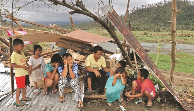 A family whose house was damaged, takes shelter under a tree covered with iron sheets along a highway in Surigao City, Surigao del Norte province, yesterday, days after Typhoon Rai devastated the city.
