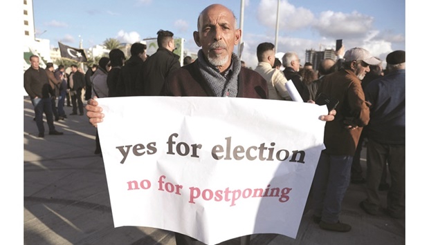 A man holds a banner during a protest against the delay to the Libyan presidential election initially planned for yesterday, in Benghazi.