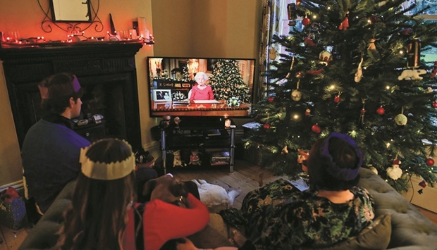 Members of a family (above) watch as Queen Elizabeth II delivers her annual Christmas Broadcast  message, at their home near  Liverpool.