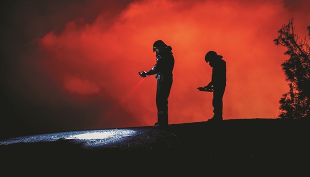 In this handout photo released on December 7 by the Spanish Military Emergency Unit (UME), members of the UME monitor gas emissions are seen following the eruption of the Cumbre Vieja volcano on the Canary island of La Palma. (AFP)