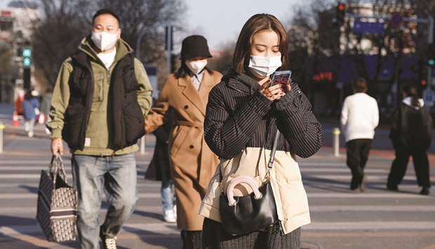 Pedestrians wearing face masks following the coronavirus disease (Covid-19) outbreak cross a street in Beijing (file). Chinau2019s economy has slowed in recent months, with the property market slump hitting debt-laden developers and also undercutting industrial output, home prices falling, and investment and private consumption weak.