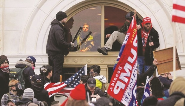 GRIM REMINDER: A mob of supporters of the-then president Donald Trump climb through a window they broke as they storm the US Capitol Building in Washington on January 6, 2021. (Reuters)