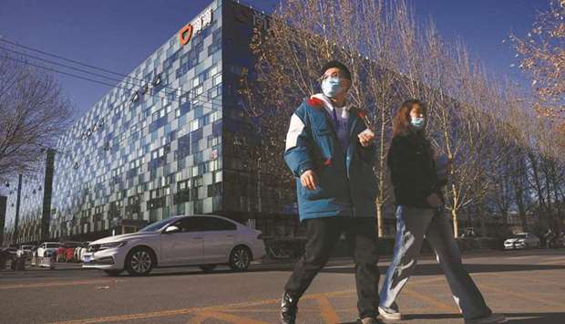 People walk past the headquarters of Didi in Beijing. The ride-hailing giant began preparations to withdraw from US stock exchanges, a stunning reversal following demands from Chinese regulators that had opposed its American listing.