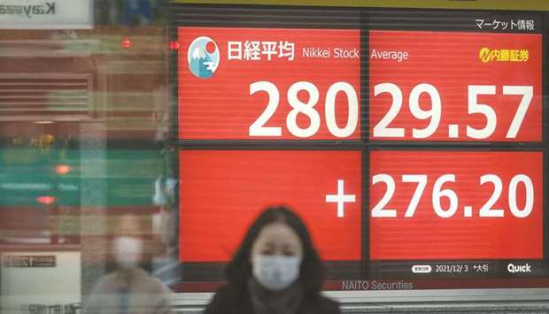 A pedestrian walks past an electronic quotation board displaying share prices of the Tokyo Stock Exchange. The Nikkei 225 closed down 1.0% to 28,029.57 points yesterday.