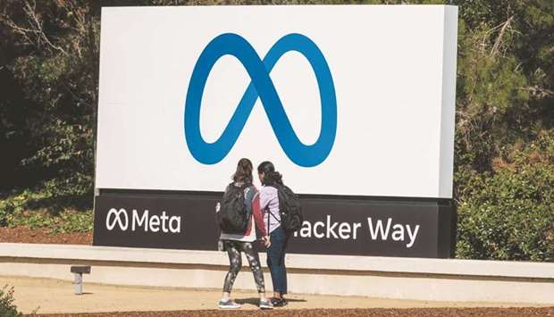 Visitors take photographs in front of signage at Meta Platforms headquarters in Menlo Park, California. Facebook parent Meta dropped on Friday, bringing its shares closer to a bear market after months of volatility triggered by a whistle-bloweru2019s revelations and disappointing quarterly results.