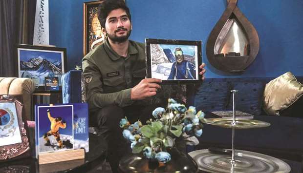 Shehroze Kashif holding a painting of himself, during the interview at his home in Lahore. (AFP)