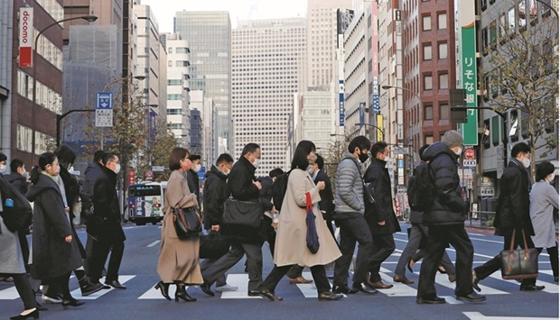 Pedestrians wearing protective masks make their way at a business district in Tokyo. Japanu2019s economy declined an annualised 3.6% in July-September, revised Cabinet Office data showed on Wednesday, worse than the preliminary reading of a 3.0% contraction.