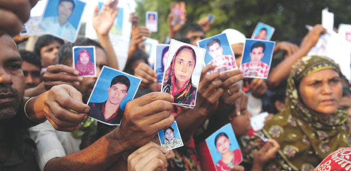 In this photograph taken on April 27, 2013 relatives holding photos of the missing and dead workers three days after an eight-storey building collapse