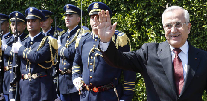 Suleiman waves for photographers as he leaves the presidential palace in Beirut yesterday.
