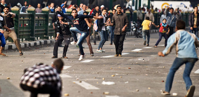 Protesters and supporters of the military regime (background) throw stones at each other during clashes yesterday in Cairo. 