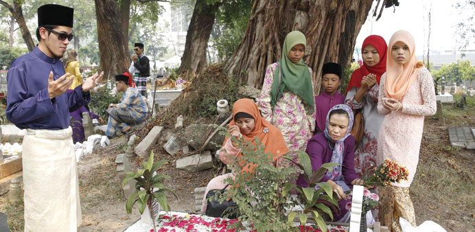 A family prays at a relativeu2019s grave on the first day of Eid al-Fitr in Kuala Lumpur yesterday.