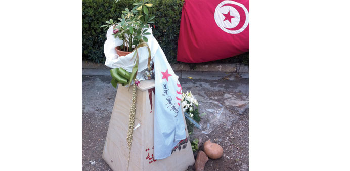 * A potted plant on a knee-high plinth, wrapped in a party flag, marks the spot in Tunis where Chokri Belaid was assassinated.