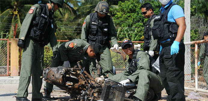 Thai bomb squad members inspect the site of a motorcycle bomb attack 